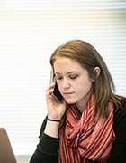 Woman talking on phone in front of laptop